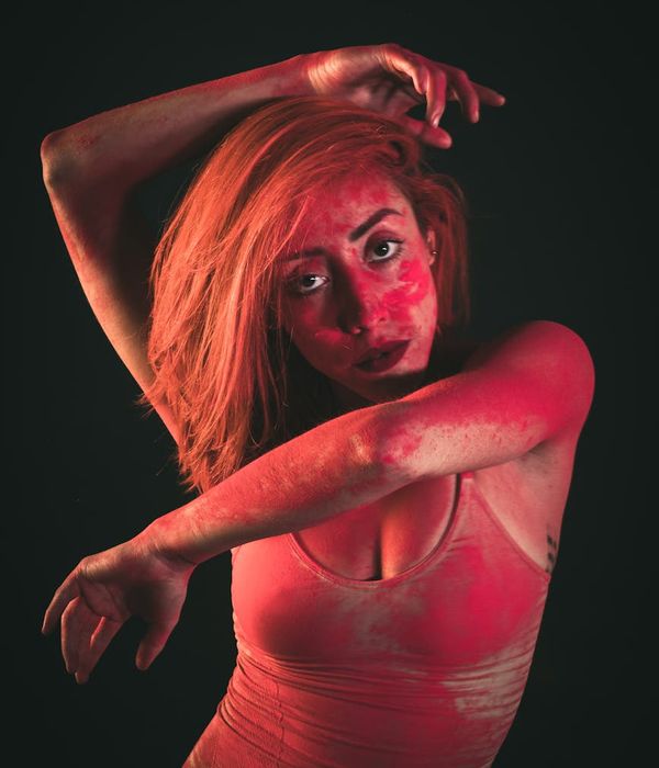 Woman performing a fluid, energetic movement in a dark studio.
